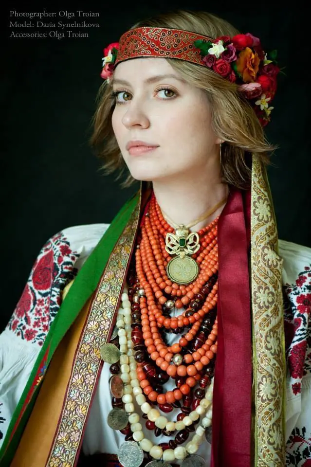 A woman in a floral headband wearing layered strands of coral korali beads over an embroidered blouse
