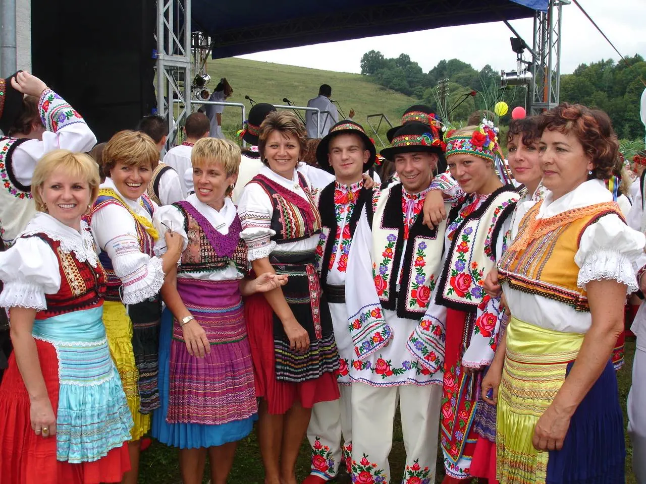 A large group of Lemko festival-goers in colorful embroidered folk dress posing outdoors
