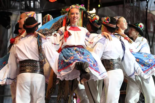 Dancers in colorful Transcarpathian costume lifting a soloist on stage