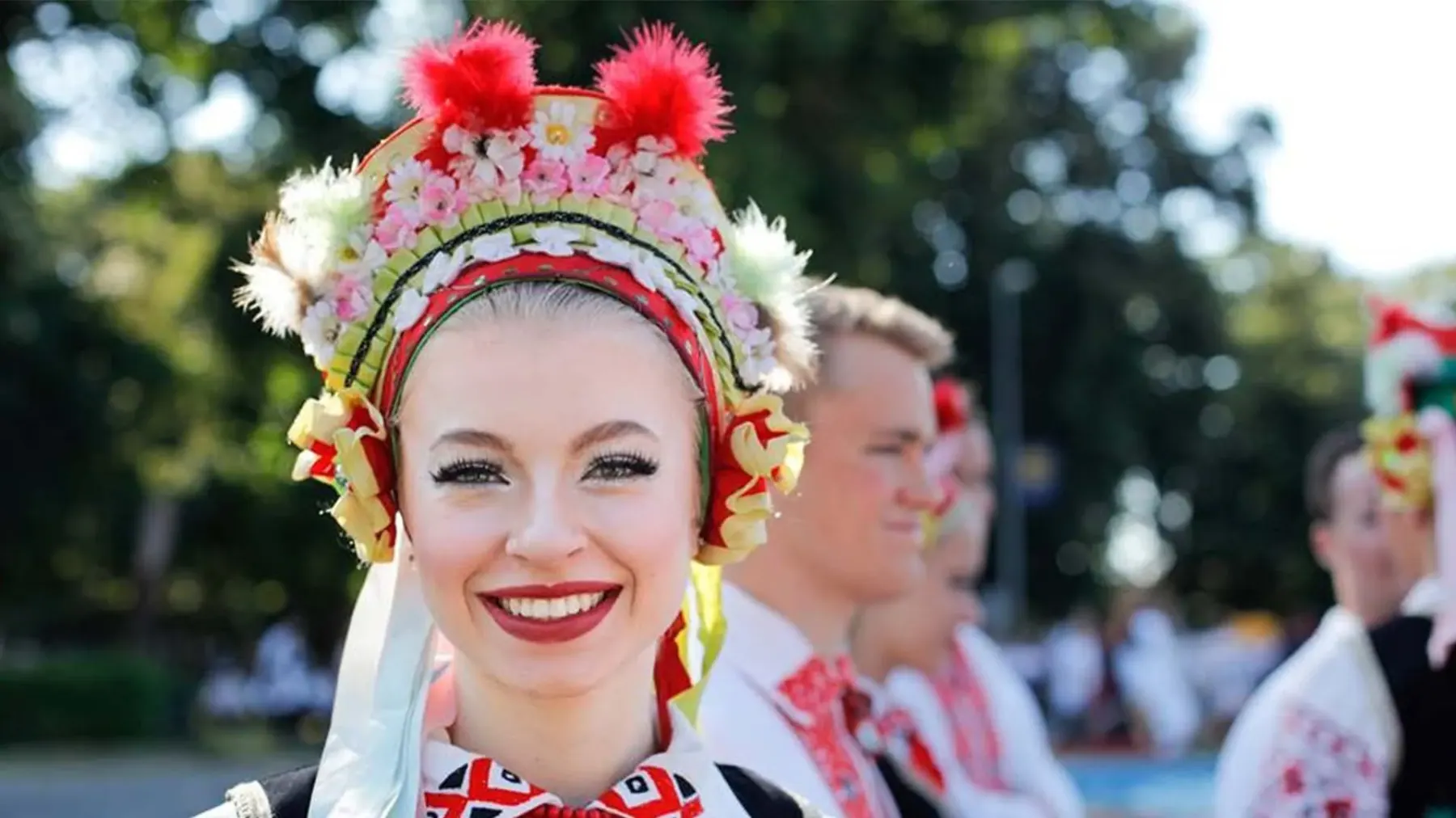 A dancer in an elaborate floral headdress and embroidered costume